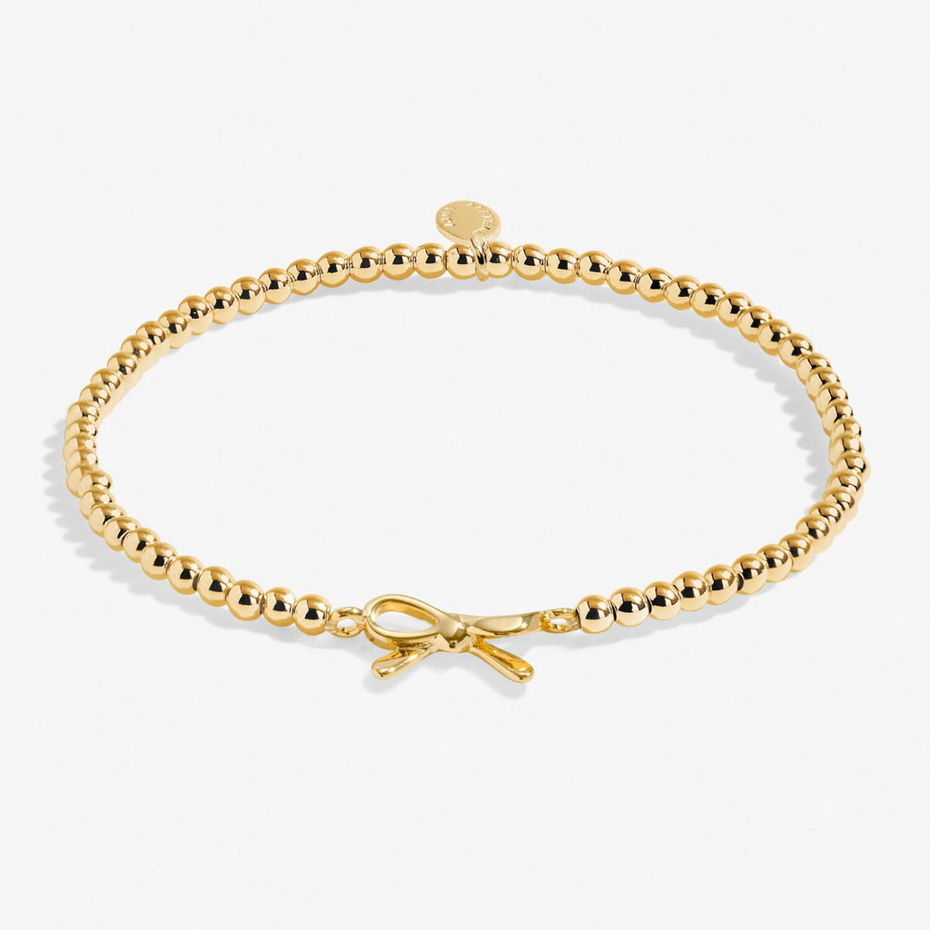 Gold bracelet with a bow charm on a white background