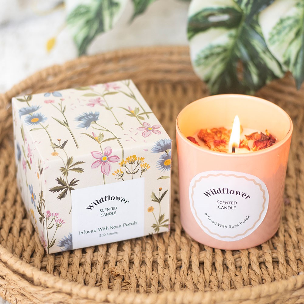 Candle with red rose petals in the wax, inside pink candle jar. Comes in a box with a white background and floral design.