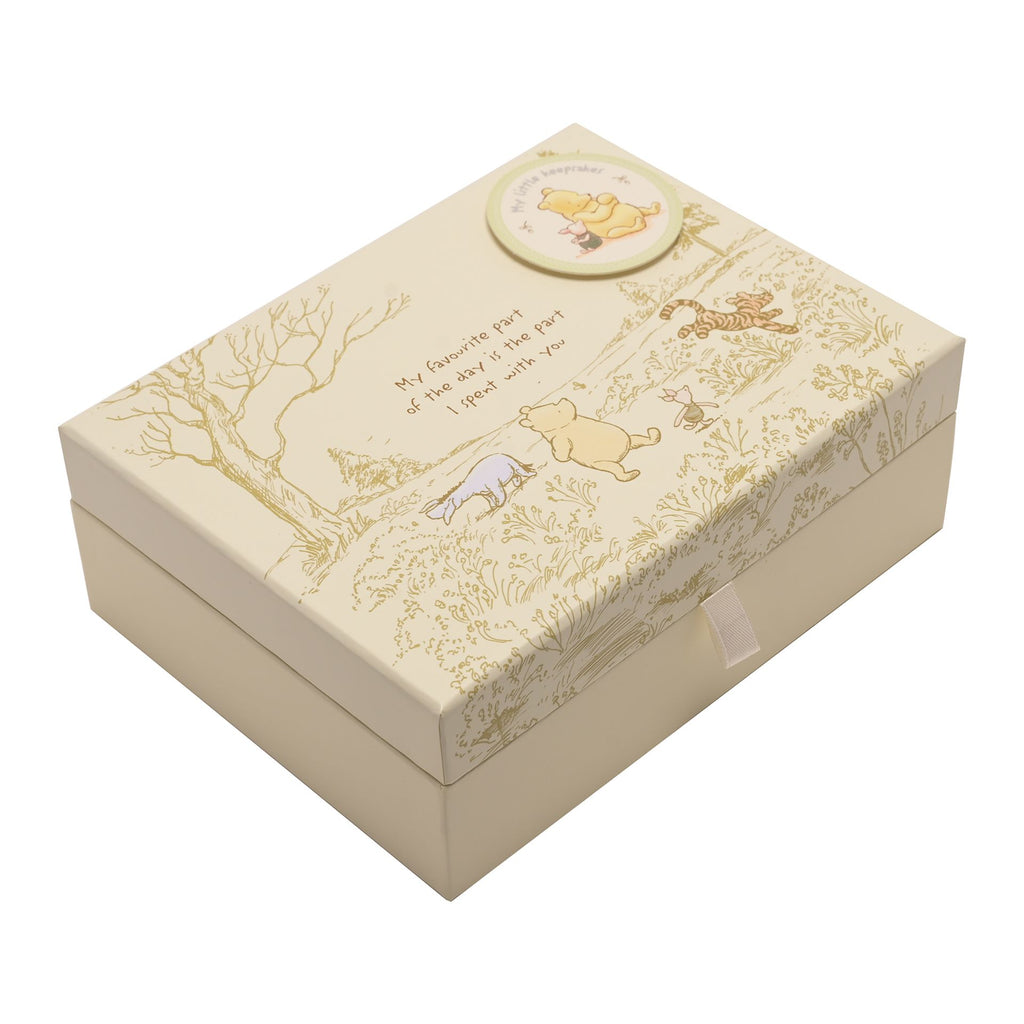 Pale yellow box with monochrome darker beige scatch of tree and grass with Winnie the Pooh, Tigger, Piglet, and Eeyore in their colours. 