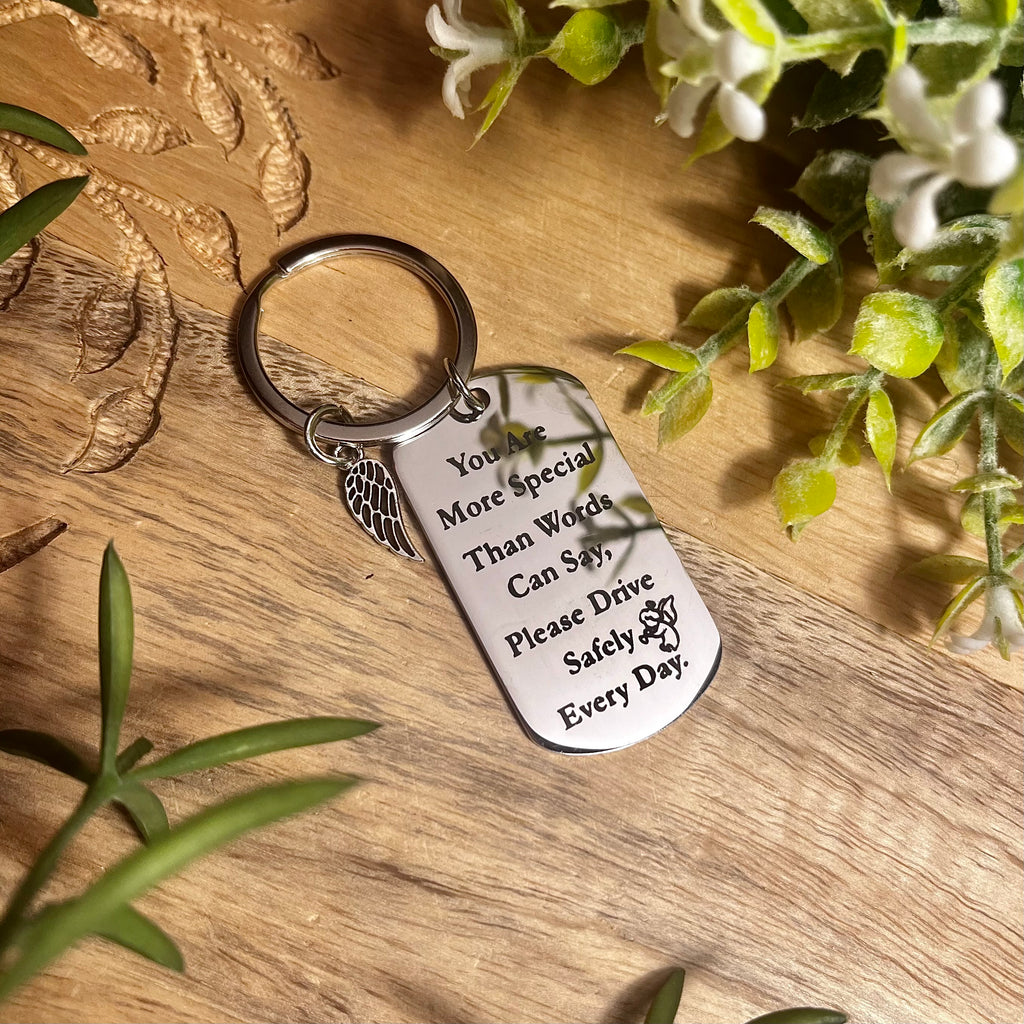 Silver keyring with silver tag engraved with ' You are more special than words can say, please drive safely every day'. Also features a small silver angel wing charm. 