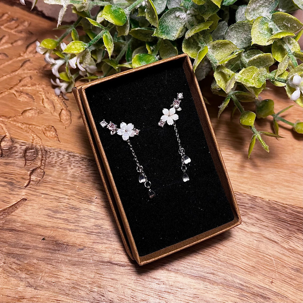 Cherry Blossom earrings with pink crystals that go up the side of the ear and a silver droplet chain with three little silver heart charms on each earring.