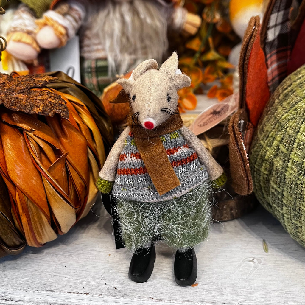 Toy mouse in a sweater with autumn decorations in the background