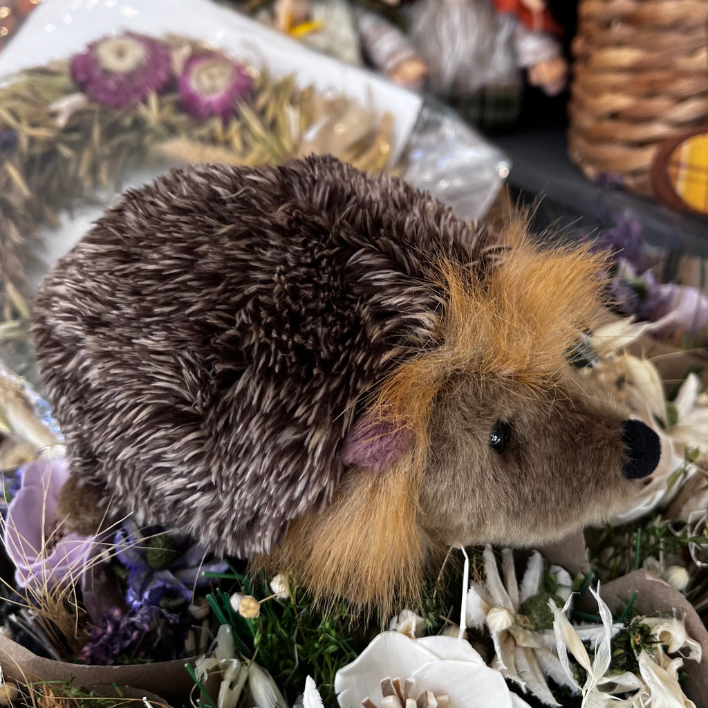 Stuffed hedgehog toy among flowers and plants