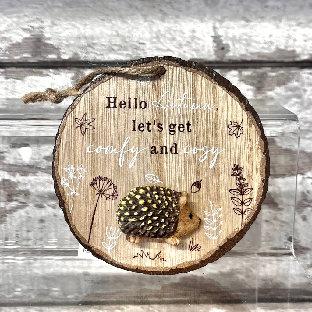 Wooden ornament with a hedgehog design and text on a wooden background