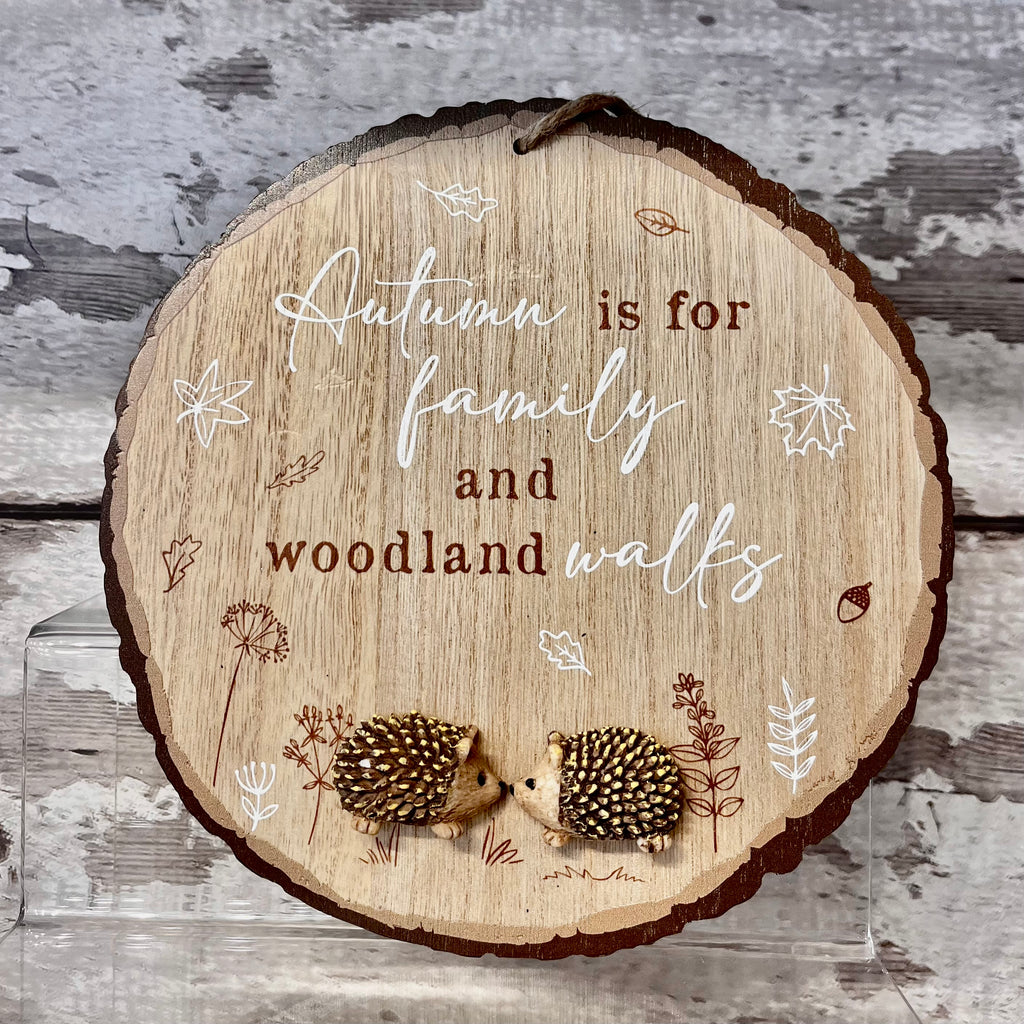 Wooden plaque with hedgehogs and autumn-themed text on a wooden background