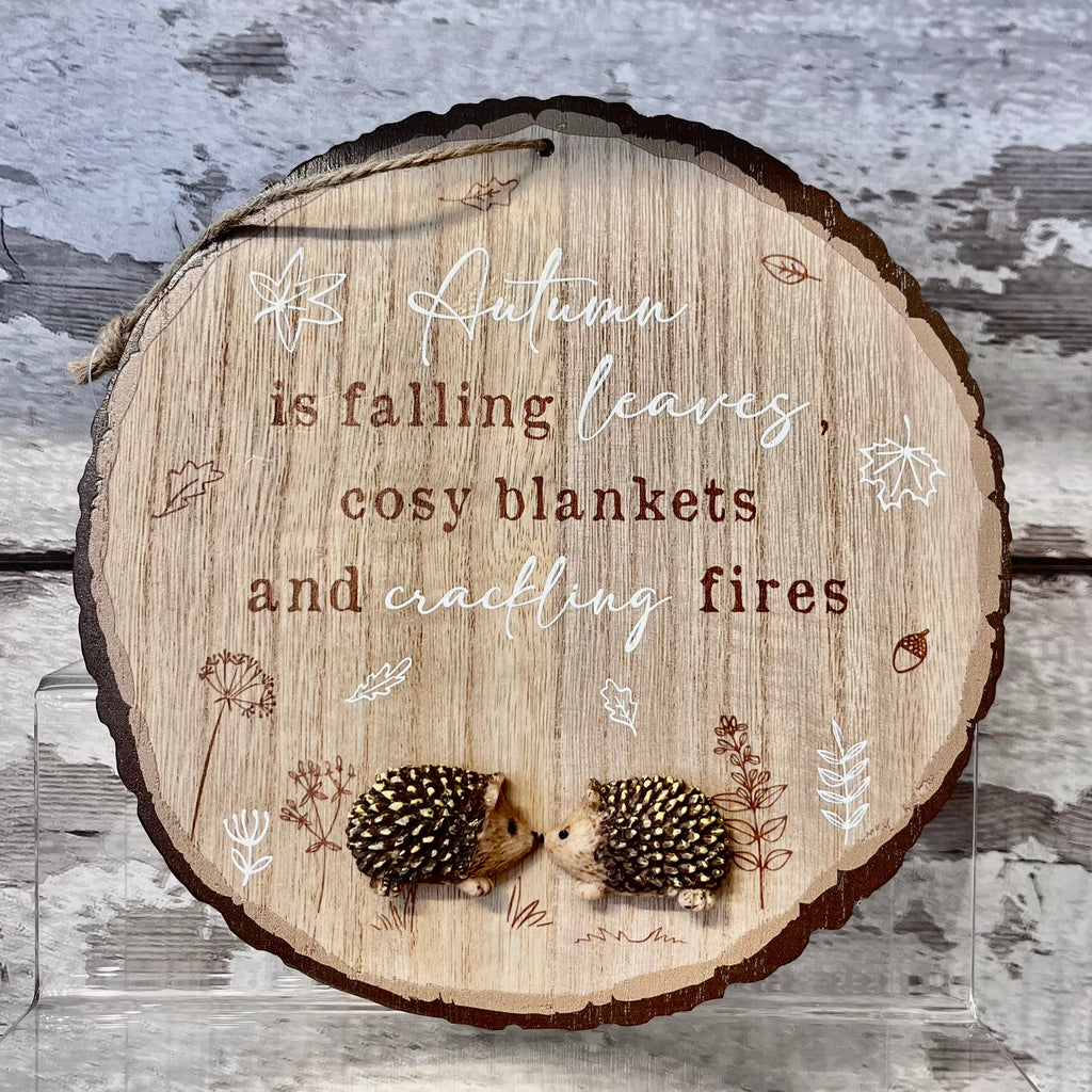 Wooden plaque with autumn-themed text and illustrations on a textured background
