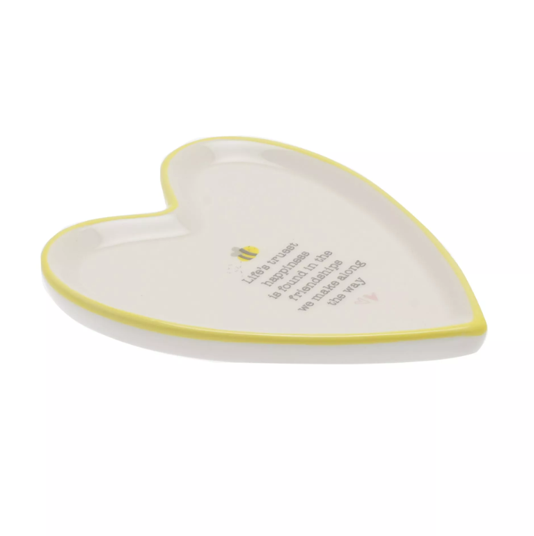 White ceramic heart shaped trinket dish with yellow border. Inside the dish features the quote 'Life's truest happiness is found in the friendships we make along the way' with a little bee illustration above the quote.