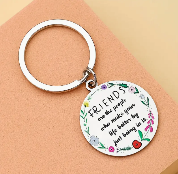 silver keyring with a round silver charm featuring a floral design around the inner circumference and engraved with the text' friends are the people who make your life better by just being in it'.