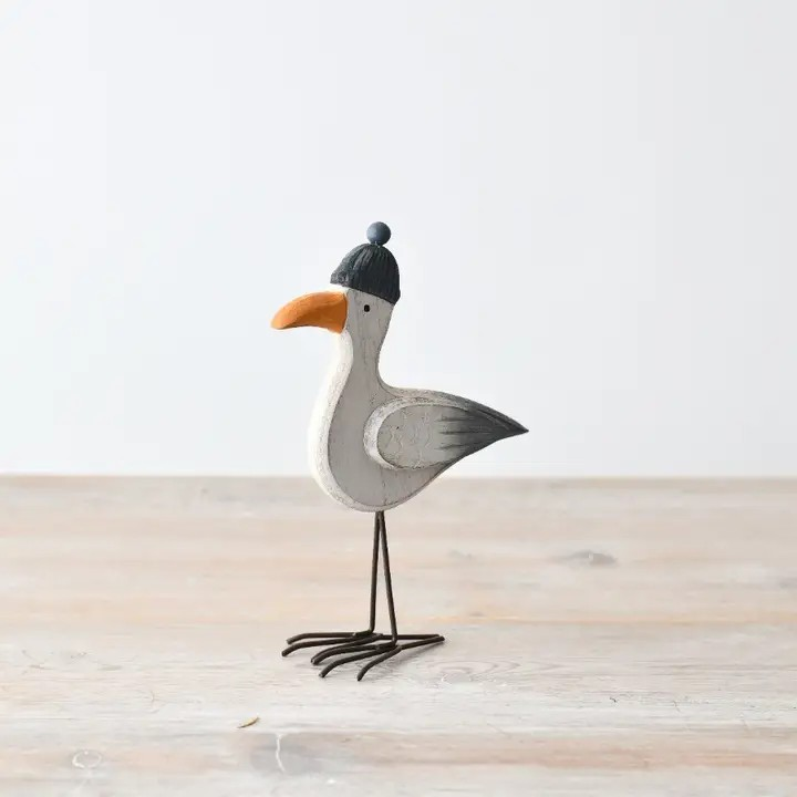Wooden seagull with metal legs wearing a beanie